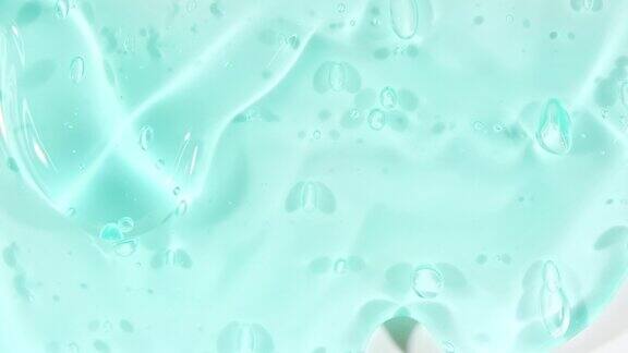 蓝色透明化妆品凝胶液与分子泡沫流动在平原白色表面微距镜头