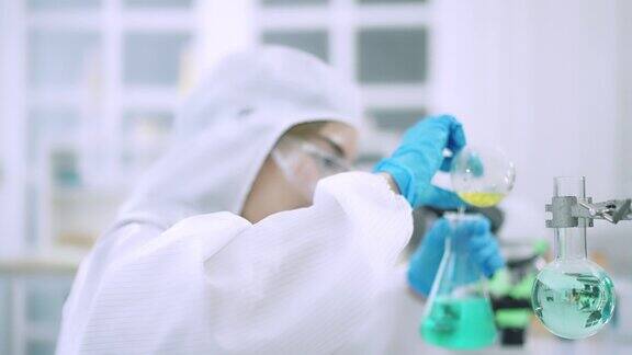 年轻的女科学家在实验室做化学实验女科学家正在小瓶中混合试剂