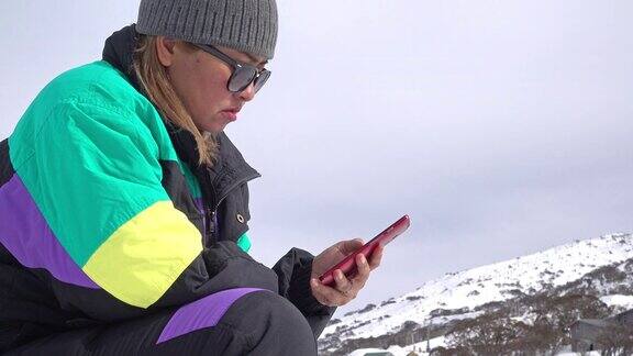 一名亚洲女性在雪山上使用智能手机