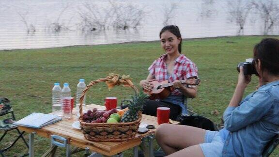 一群亚洲朋友玩尤克里里和花时间在夏季假期野餐他们在假期很快乐玩得很开心