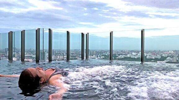 亚洲女人躺在喷泉温泉在高层豪华公寓的游泳池