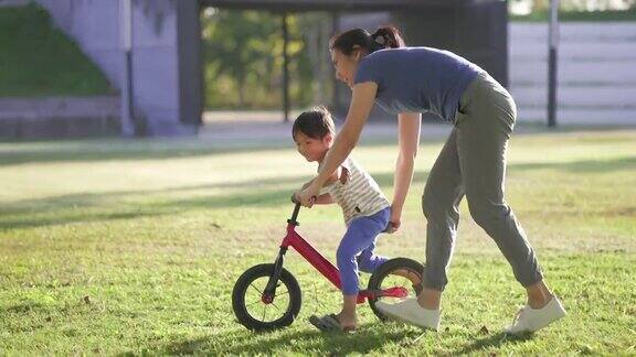 母亲在公园教儿子骑自行车