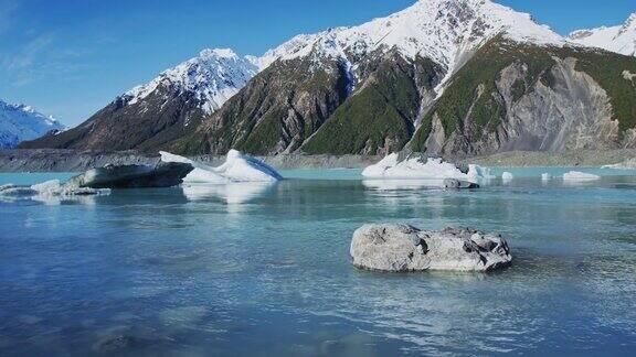 冰山漂浮在冰川泻湖与雪山的背景