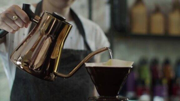 可爱的日本咖啡师将热水倒在磨碎的咖啡豆上(慢镜头)