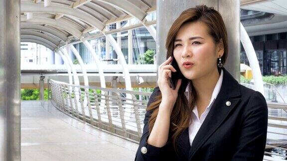 美丽的亚洲女商人手拿智能手机在外面的现代城市