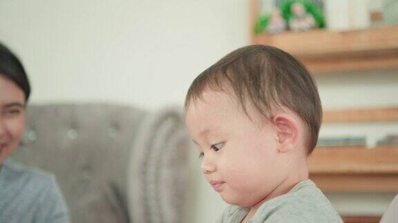 可爱的亚洲新生儿坐在高脚椅上吃饭而母亲的手喂食物给孩子在家里
