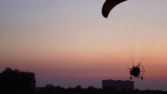 飞行员在一个滑翔伞飞行从相机逐渐移到远处的日落美丽的天空