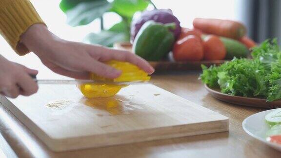 用锋利的刀在木板上切黄辣椒的特写镜头