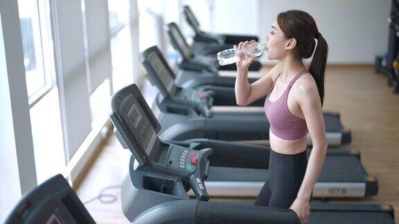 健康的亚洲女性在健身房的跑步机上跑步