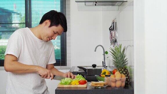 年轻人在家里厨房切菜准备健康食物