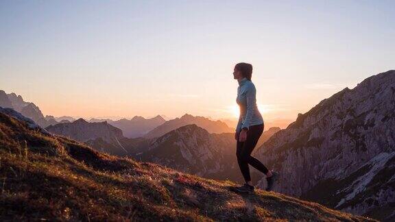 健康的女性运动员保持健康的生活方式在日落时在岩石小径和草坡的山上徒步旅行
