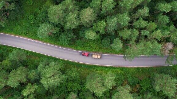 农用拖拉机农用机械农业自然季节性工程鸟瞰图农用拖拉机沿着农村公路通过夏季森林红色拖拉机在波兰的森林道路上搬运干草
