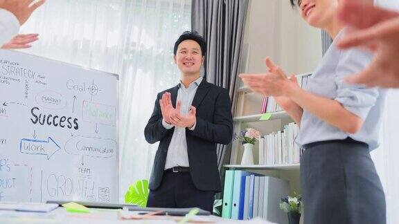 亚洲商人领导在会议室进行头脑风暴时将白板上的工作汇报给同事团队一群员工鼓掌感谢公司同事在会议上的讨论