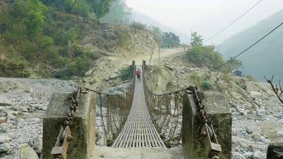 两名背包客在尼泊尔的一座悬空金属桥上行走