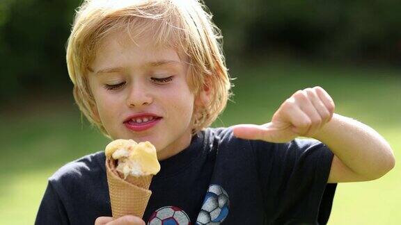 金发小男孩一边吃冰淇淋一边竖起大拇指