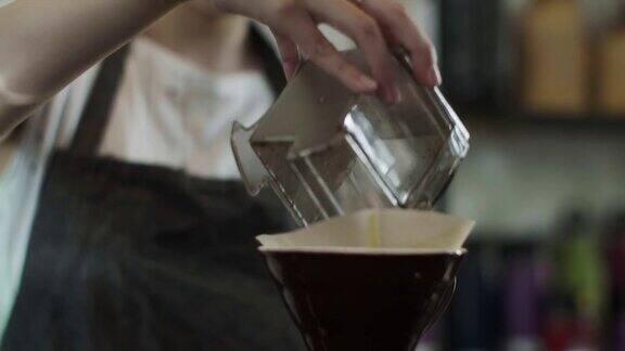 可爱的日本咖啡师倒磨碎的咖啡豆(慢镜头)