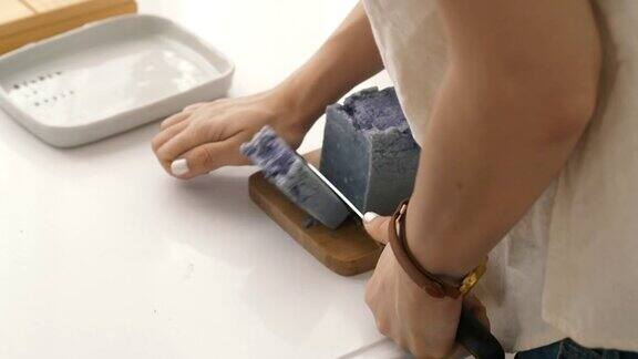 亚洲妇女的小生意是制作有机肥皂的过程中切割同时使用硬木制面包肥皂刀具手工精密切割肥皂修剪她的手工肥皂在她的房间
