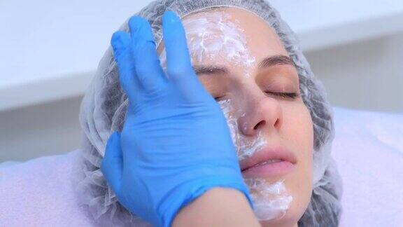 美容师正在用麻醉膏涂抹在病人的脸上特写的手