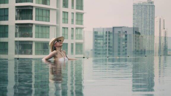 美丽的亚洲女性游客住在酒店房间的游泳池里