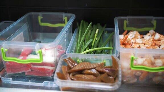 食物前视图特写镜头塑料容器中的海鲜蟹条黄瓜片鱼鳗鱼水煮虾制作寿司的半成品烹饪