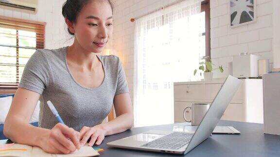 亚洲美丽的女人在休闲服装使用笔记本电脑为她的工作在家工作远程工作和自我隔离新的家庭办公室设置