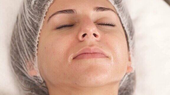 美容医学治疗治疗师用手在客户脸上涂抹霜