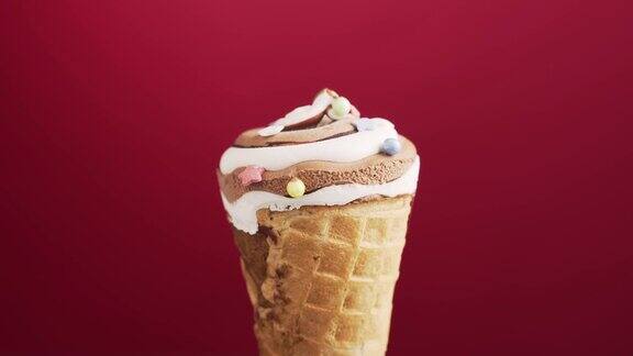 巧克力冰淇淋蛋卷在红色背景上旋转彩色的糖屑落在美味的自制咖啡冰淇淋上