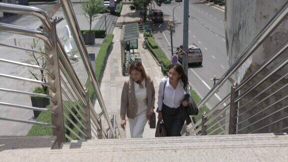 两个亚洲女商人走在天桥上