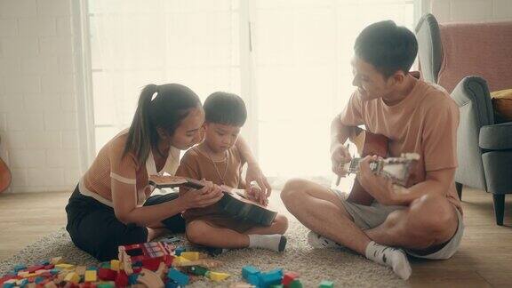 温馨的家庭教育时刻:快乐的家庭儿子弹吉他创造回忆
