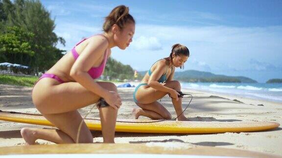 4K一群亚洲女性戴着冲浪板安全绳一起在海里冲浪