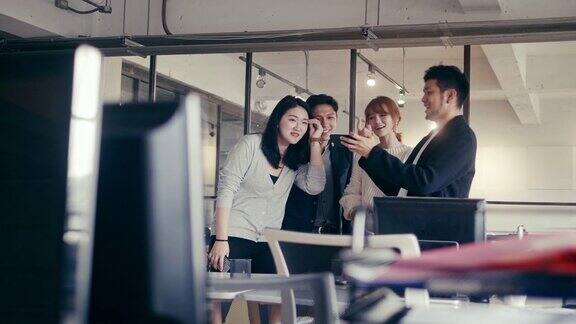 一群亚洲千禧一代在金融科技公司办公室用智能手机看视频(慢镜头)