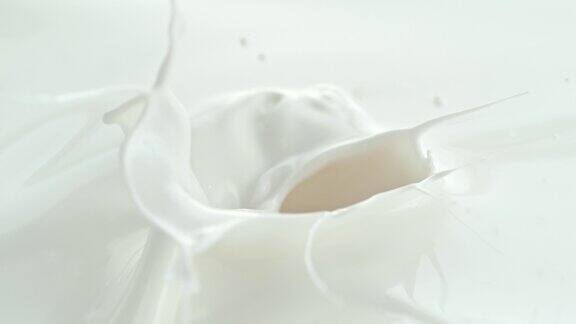 在微距和慢镜头中半桃子落入奶油牛奶中形成漩涡飞溅