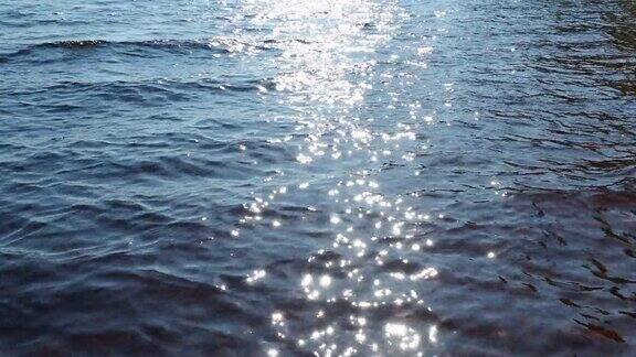 水虚化背景涟漪阳光照在波浪上海的涟漪太阳模糊的眩光在蓝色的水面上光斑:光的反射或光斑放松的视频柔和的波浪阳光路径