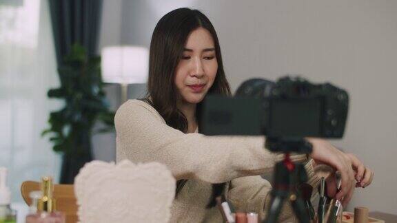 亚洲年轻的女博主在家里录制Vlog视频和直播化妆教程名人影响者概念