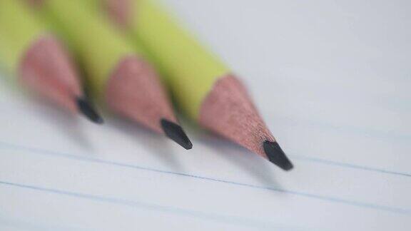 宏观视频的旋转石墨铅笔在一个开放的笔记本在尺子的空页上的特写