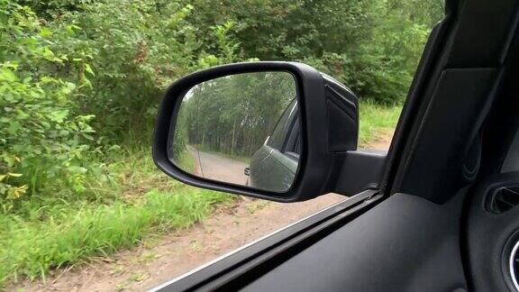 汽车行驶在道路上穿过绿色的夏季森林道路是反射在侧镜