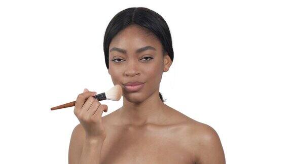 迷人的非洲裔美国女性使用化妆刷化妆美丽孤立在白色背景上