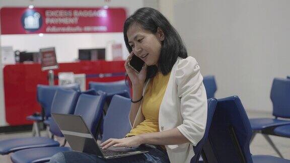 年轻的亚洲商务女性在国际机场候机楼门口等待航班起飞时用手提电脑检查出差计划和航班时刻表确认与同事的会议文件