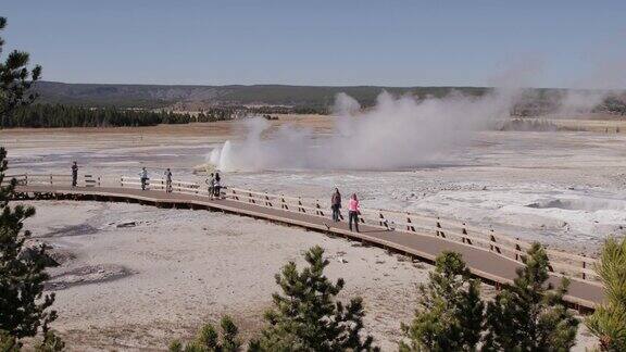 游客观看黄石国家公园中一处间歇泉喷发的延时镜头