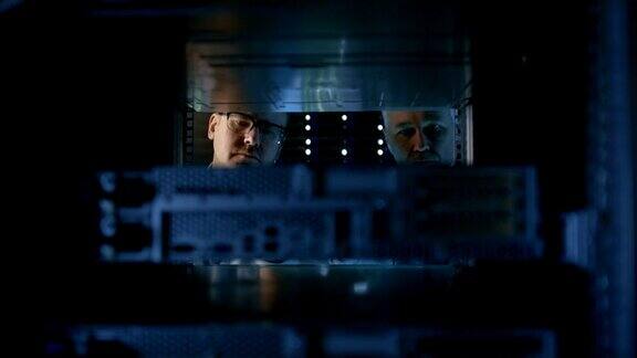 2名服务器工程师在服务器机架安装硬件他们在大型现代数据中心工作