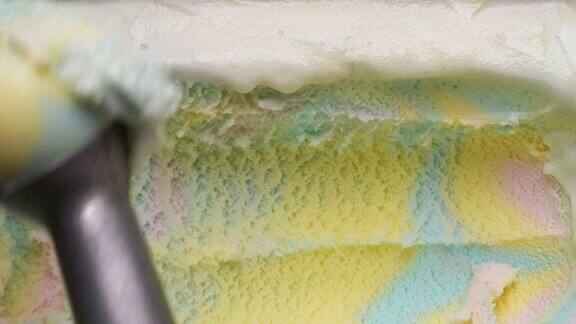 彩虹冰淇淋被金属勺子从容器中舀出