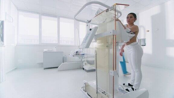在医院乳房x光检查技师医生在乳房x光检查机上按下按钮激活女性患者扫描医生解释预防乳腺癌筛查的重要性现代技术先进的诊所