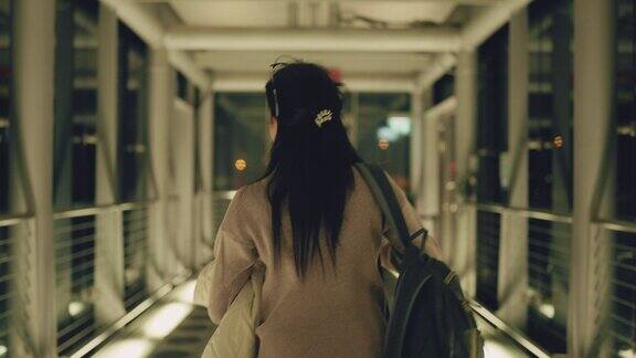 一名亚洲女子拖着行李走过国际机场候机楼的玻璃大厅