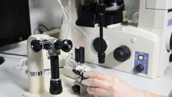 现代医学实验室中的生殖医学生育专家执行icsi体外受精程序移动操纵杆来调整微型操纵针人工授精4k的视频