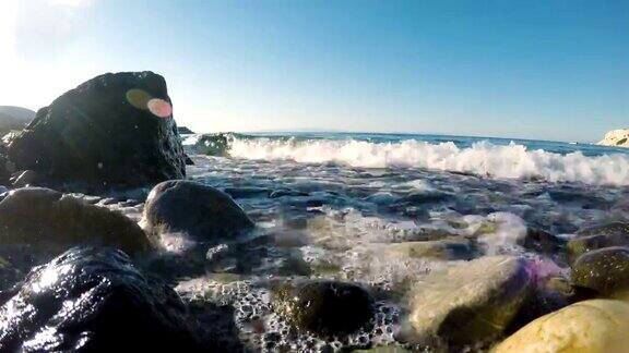 海浪和水溅到靠近水边的多石海滩上的石头上