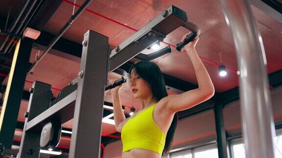 美女在健身中心做引体向上运动年轻的亚洲妇女穿着运动服在健身房锻炼