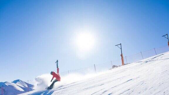 在一个晴朗的阳光明媚的日子里滑雪者沿着滑雪坡滑行留下了一层粉末雪云