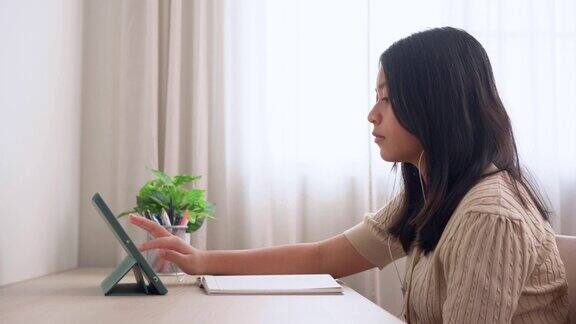 亚洲女孩准备和设置一个数字平板电脑在家里学习在线学习家庭教育理念