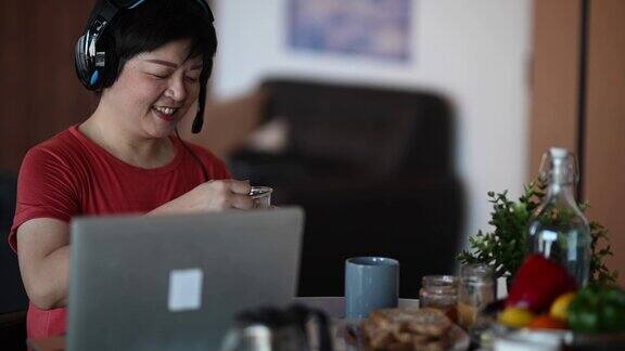 一位亚洲华人中年人在餐厅吃早餐早上用笔记本电脑回复电子邮件