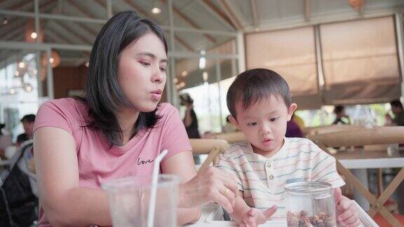 亚洲男婴与母亲在餐厅用餐